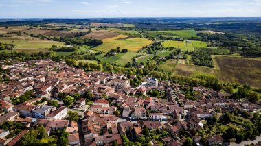 Aerial view showing small town rooftops beside green rural farmland landscape