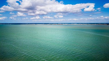 Sakin turkuaz okyanus uzak kumlu kıyılara doğru uzanıyor.