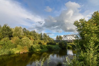 Nehir üzerinde demiryolu köprüsü olan yaz günbatımı manzarası. Geniş açı. Mavi gökyüzünün arkaplanı.