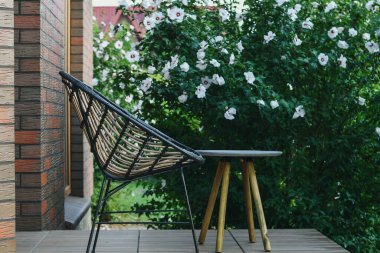 Hasır sandalyeleri ve kahve masasını bahçenin arka planında gevşetiyorum. Kapat..