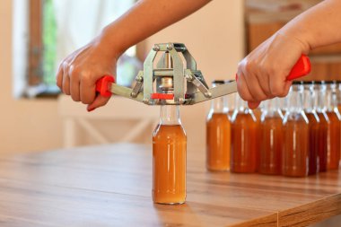 Ev yapımı için el kapağı kullanıyorum. Ev yapımı içki ya da alkol içeren kahverengi şişelerin arka planı. Seçici odak.