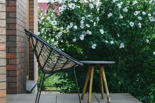 Hasır sandalyeleri ve kahve masasını bahçenin arka planında gevşetiyorum. Kapat..