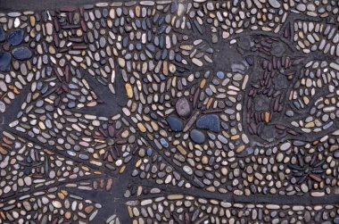 Küçük, koyu renkli çakıl taşlarından yapılmış bir kaldırımın üst görüntüsü.