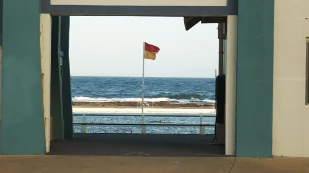 在澳大利亚纽卡斯尔的海洋浴场冲浪拯救生命的旗帜和游泳者 — 图库视频影像