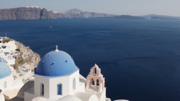 Blå kupade kyrkan på Oia på Santorini med fira i fjärran — Stockvideo