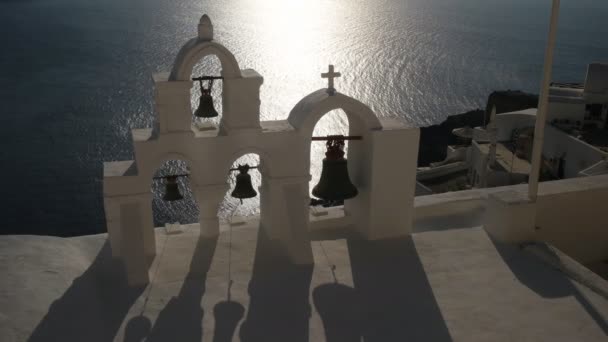 Bliska czterech dzwonów kościelnych o zachodzie słońca na wyspie Oia, Santorini — Wideo stockowe