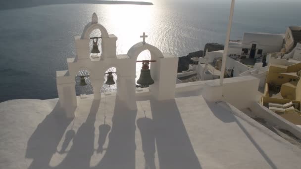 Fyra klockor och skuggor vid solnedgången i Oia, Santorini — Stockvideo