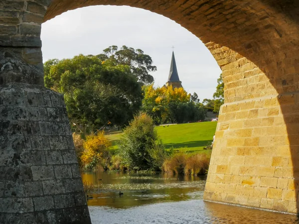 Vista ravvicinata del vecchio ponte storico in pietra e della guglia della chiesa cattolica di San Giovanni — Foto Stock