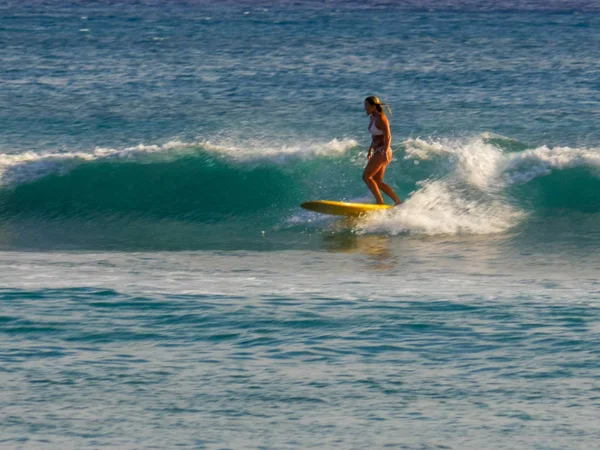 WAIKIKI, ESTADOS UNIDOS DA AMÉRICA - 9 DE AGOSTO DE 2015: uma mulher monta um longboard na praia de waikiki — Fotografia de Stock