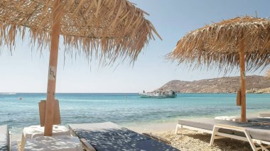 beach chairs at elia beach on mykonos, greece clipart