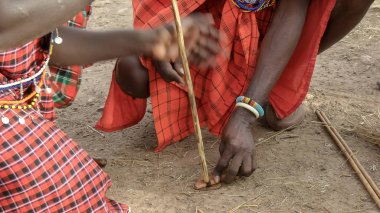 iki maasai erkek kenya bir manyatta bir yangın başlatmak için bir el matkap kullanın