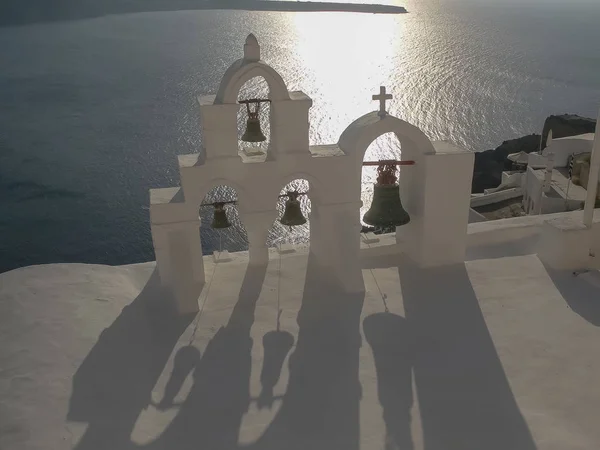 Cuatro campanas y sombras al atardecer en oia, santorini —  Fotos de Stock