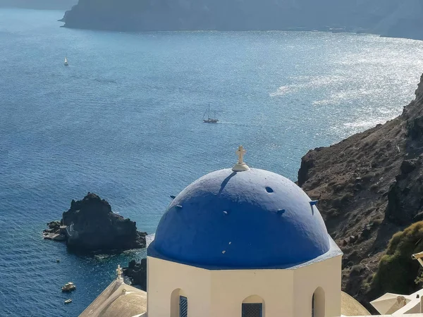 Niebieski kopułą Kościół z jachtem w tle w Oia, Santorini — Zdjęcie stockowe