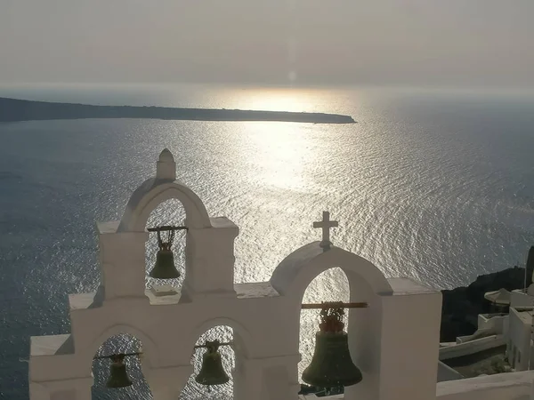 Sol en el océano y cuatro campanas de la iglesia en oia, santorini —  Fotos de Stock