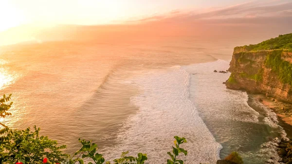 Uluwatu templo al atardecer con el sol brillando en romper las olas en Bali —  Fotos de Stock