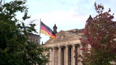 Berlin, Almanya 'da ağaçlar tarafından çerçevelenmiş Reichstag ve Alman bayrağı