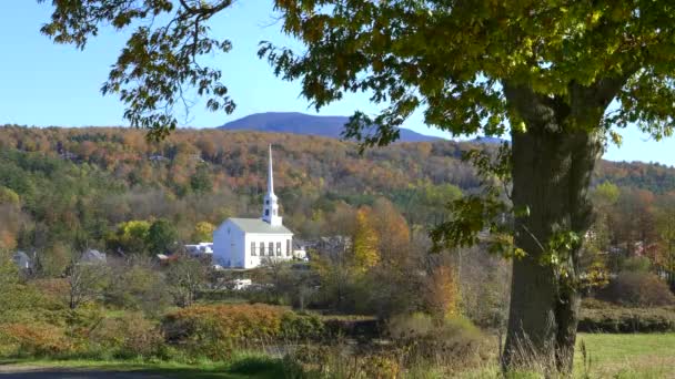 나무로 둘러쌓여 있고 가을 잎 이 있는 언덕 이 있는 화덕에 있는 하얀 교회 — 비디오
