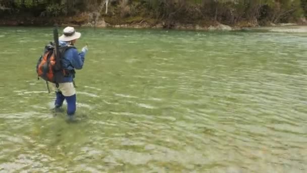 Female fisherman fighting a large trout on a river in new zealand — Stock Video