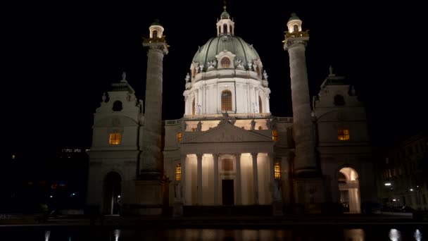Close night shot van St Charles kerk weerspiegeld in een zwembad bij Vienna — Stockvideo