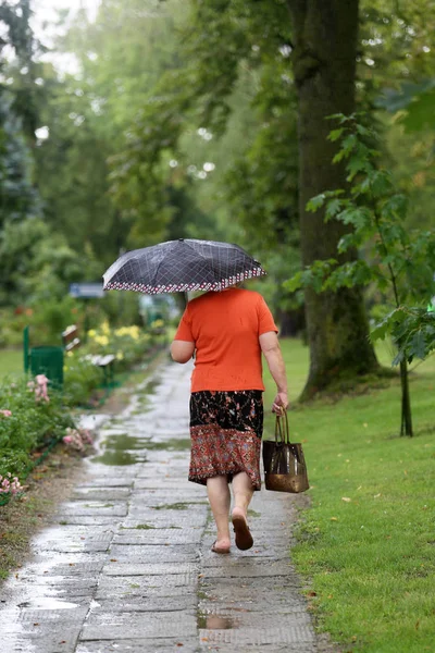 An elderly woman got wet after a sudden rain