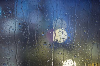 Damla yağmur pencerede, gece. bulanık ışık