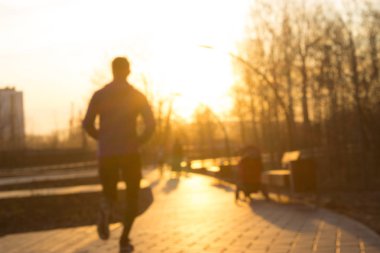 Günbatımı sırasında parkta koşan genç adam. Bulanık resim
