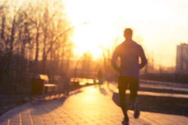 Günbatımı sırasında parkta koşan genç adam. Bulanık resim