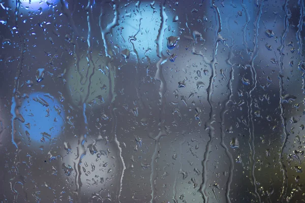Damla yağmur pencerede, gece. bulanık ışık