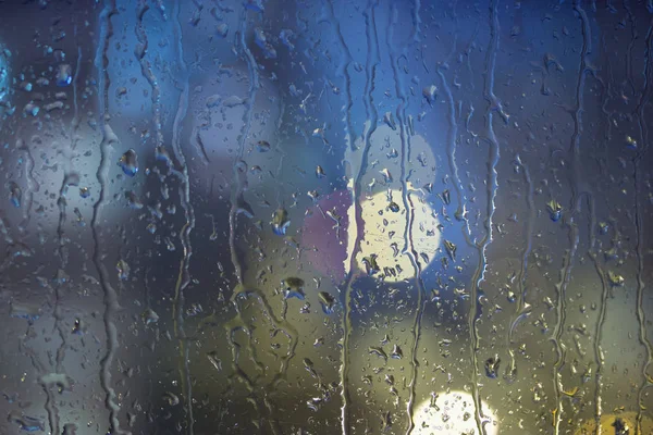 Damla yağmur pencerede, gece. bulanık ışık