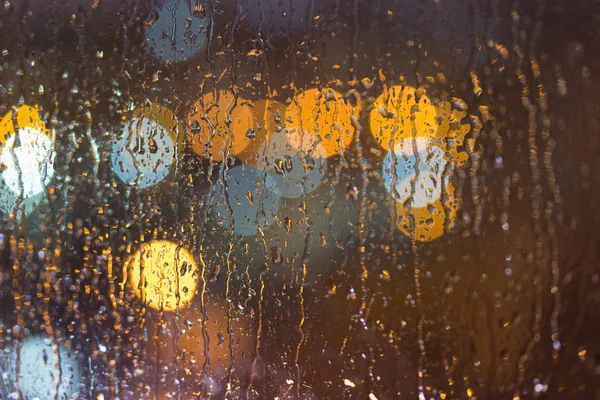 Drops of rain on window, night. blurred light