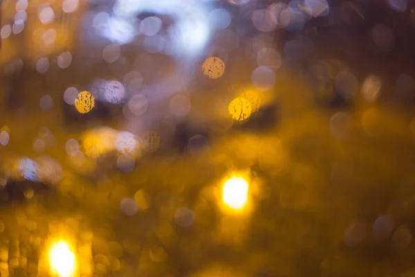 Drops of rain on window, night. blurred light