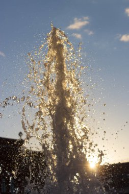 Çeşme su sıçramalarına güneşli bir günde. arkadan aydınlatmalı