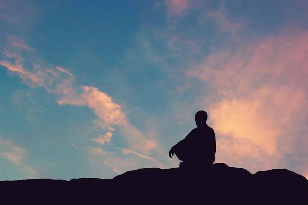 man meditating pastel on high mountain in sunset background.