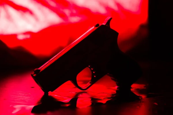 High contrast image of a bloody crime scene with gun on the floor