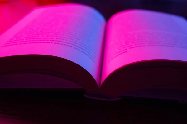 Aufgeschlagenes Buch Mit Rosa Neonlicht Über Dunklem Hintergrund — Stockfoto