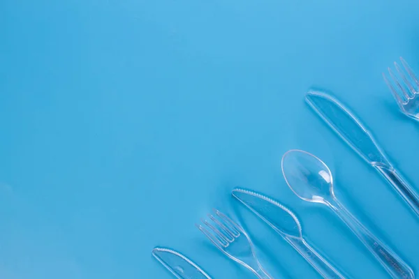 Πλαστικά πιρούνια και μαχαίρια σε μπλε φόντο — Φωτογραφία Αρχείου