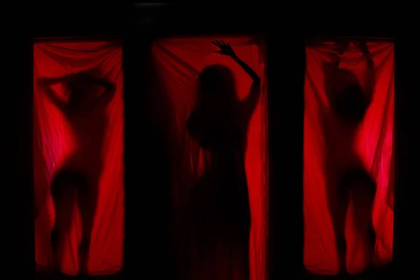 Woman behind red curtains