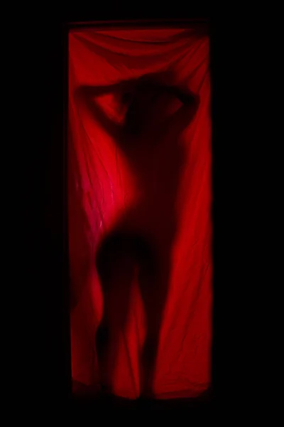 Woman behind red curtains