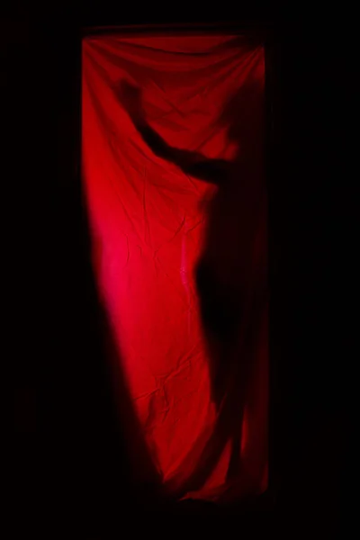 Mulher atrás de cortinas vermelhas — Fotografia de Stock