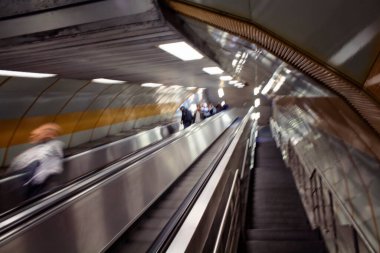 İstanbul metrosunda yürüyen merdivendeki insanların bulanık görüntüsü.