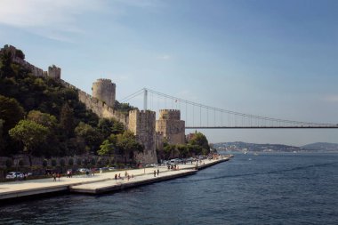 İstanbul 'da Boshorus, FSM köprüsü ve Rumelihisari veya Bogazkesen Kalesi' nden (ortaçağ kalesi) geçen insanların görüntüsü. Güneşli bir yaz günü..