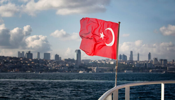 View o Turkish flag waving on a ferry boat with the cityscape of European side of Istanbul.