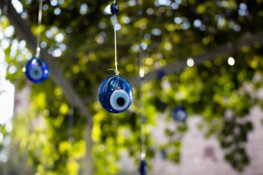 Evil eyes are hung in decorative purpose with a tree in the background in Cunda (Alibey) island. clipart