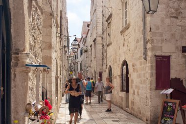 Şapkalı ve çok sayıda turist olan siyah elbiseli kadın Dobrovnik 'in eski kasabasında sokakta yürüyor. Hırvatistan 'ın güneyinde Adriyatik Denizi' ne bakan bir şehir..