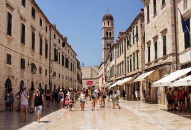 Birçok turist, güneşli yaz gününde Dubrovnik 'in eski büyük caddelerinden birinde (Stradun) yürüyor..
