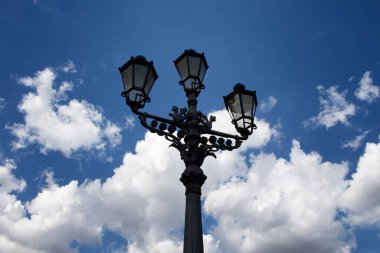 Eski, tarihi, süslemeli sokak lambası Berlin 'in alt manzarasından. Arka planda mavi, bulutlu bir gökyüzü var. Simetrik bileşim.