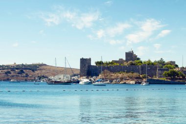 Bodrum kalesinin önündeki turkuaz suya park edilmiş lüks yatlar (yelkenli tekneler). Görüntü Ege ve Akdeniz kıyı yaşam tarzının kültürünü gösteriyor.