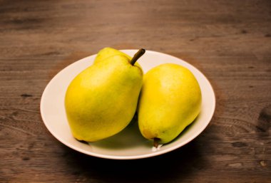 Armutlar ahşap masada beyaz porselenler.