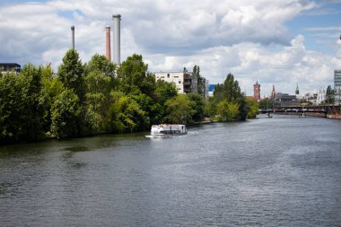 Berlin 'deki Spree River' da turistik tur teknesi. Arka planda şehir manzarası var.