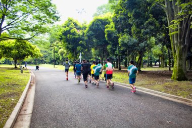 İnsanlar Tokyo 'daki Yoyogi parkında doğada koşuyorlar.
